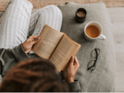 Adult reading in cozy chair with coffee and glasses