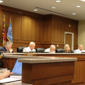 Five Dare County commissioners sit at the dais during a meeting