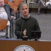 Image of Lee Nettles speaking at a podium during the meeting.