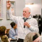 Image of Chairman Bob Woodard speaking to a crowd of people using a microphone.