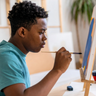 Image of a teenage boy painting on canvas.