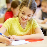 Image of a smiling young girl writing in a notebook.