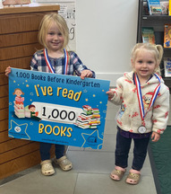 Two smiling children holding "I've read 1000 Books Before Kindergarten" sign
