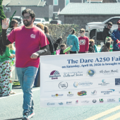 A250 Volunteer walking while waving and holding a banner.