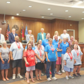 Image of special olympics athletes wearing competition medals posing with volunteers.