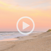Image of a beach at sunset. A play button graphic signifies that a video about beach nourishment will play when clicked.