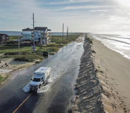 Image of an ambulance driving through standing water in a roadway after a storm.