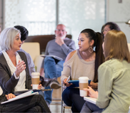 Image of three adult women sitting together, drinking coffee in discussion.