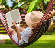 Image of a woman reading a book while laying in a hammock.