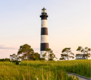 Image of the Bodie Island Lighthouse, surrounded by marsh grasses.