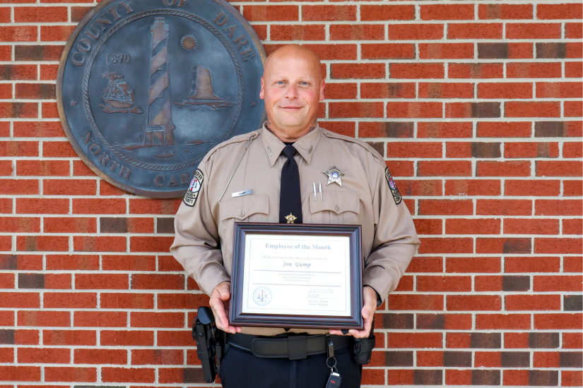 Deputy Gump holds his certificate in front of the Dare County bronze seal.