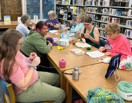 Adults at Knit Knights gathering working on fiber arts projects at KDH Library