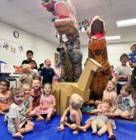 Costumed dinosaur with group of happy kids