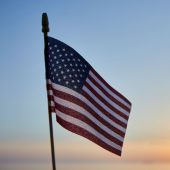 Image of an American flag against a sunset sky.