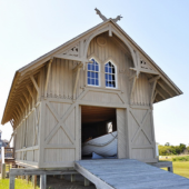 Image of the wooden Chicamacomico Lifesaving Station boat house. A row boat sits inside the open barn door.