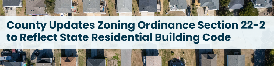 Aerial image of house roofs. Subheading reads: County Updates Zoning Ordinance Section 22-2 to Reflect State Residential Building Code