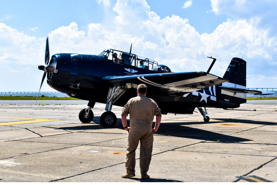 Image of a man standing on a tarmac, looking at a Commemorative Air Force airplane.