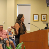Image of a young woman speaking at a podium.
