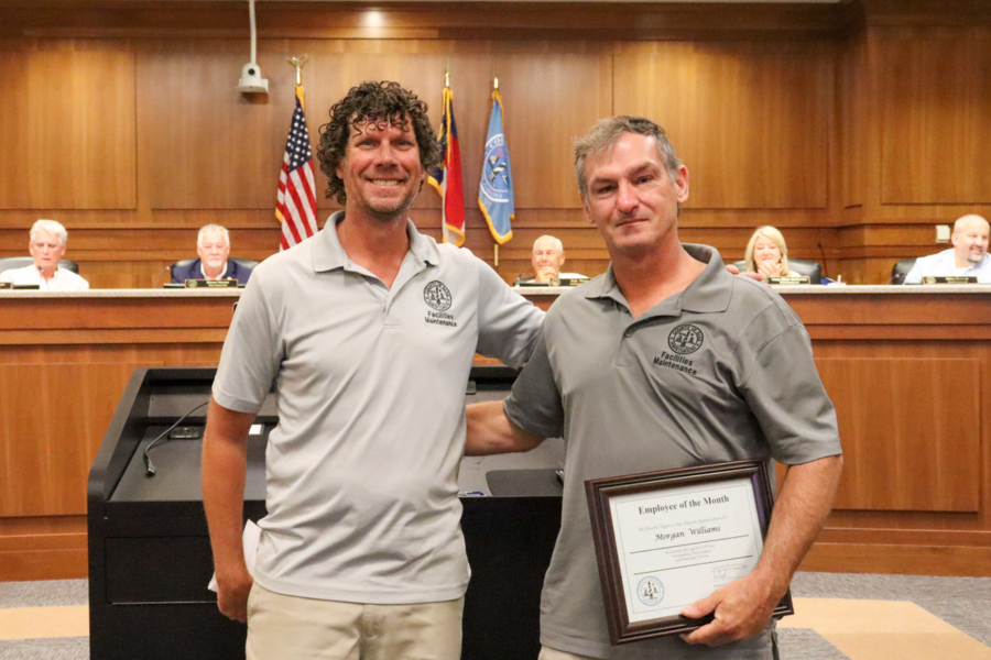Morgan and Gordon stand together in front a of a bronze Dare County seal.