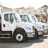 Image of three county trash trucks parked in a line.