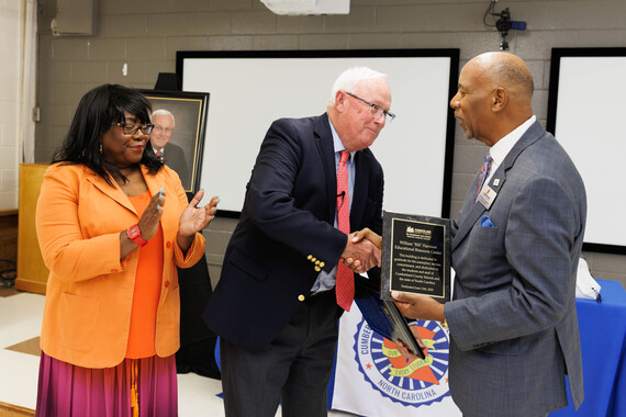 Dr. Harris accepts receives a plaque from Board Chairwoman Jones and Dr. Connelly 