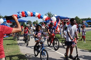 Families enjoy the bike parade at the Fourth on First Avenue event