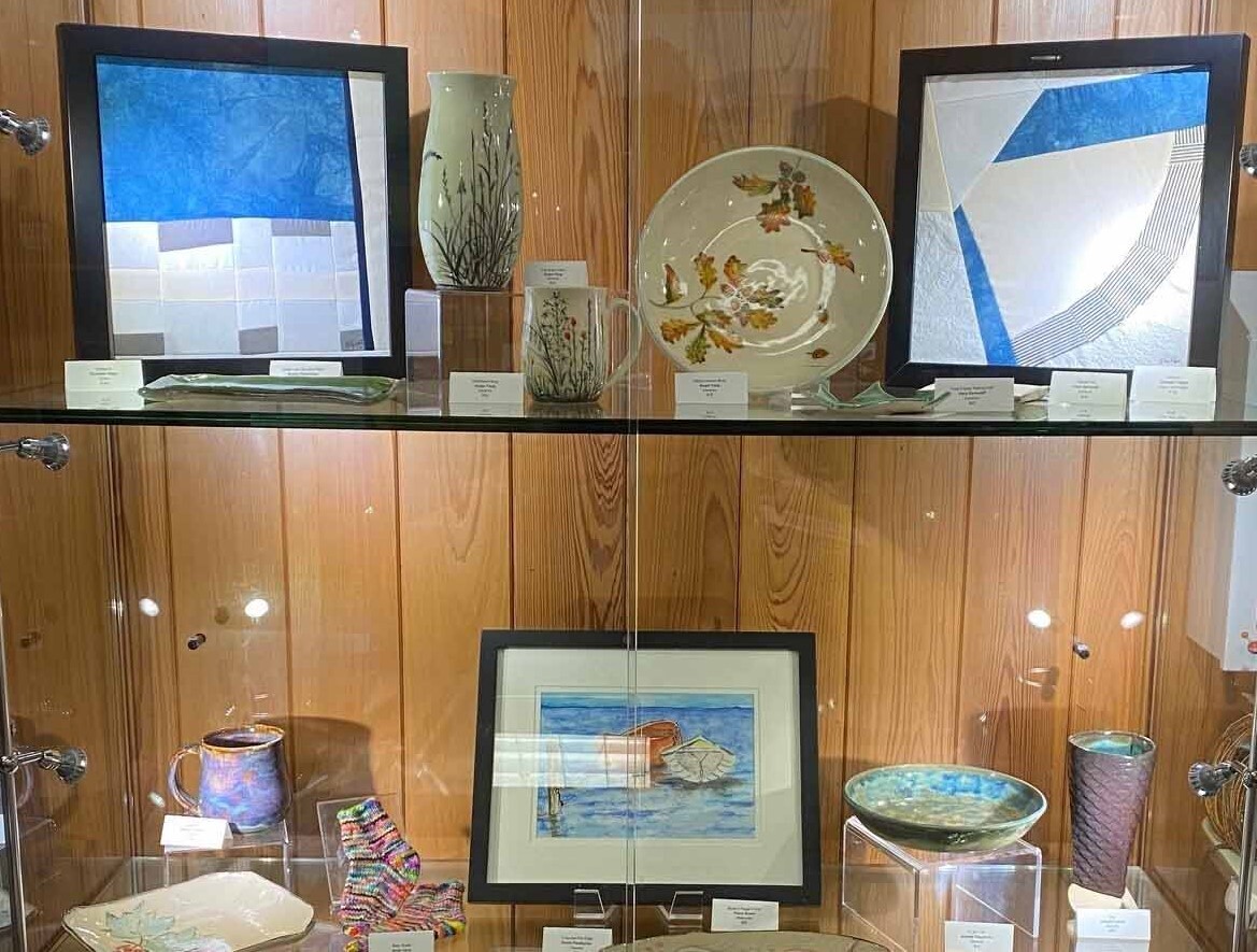 Glass display case with handmade ceramics, fibers and small paintings. 