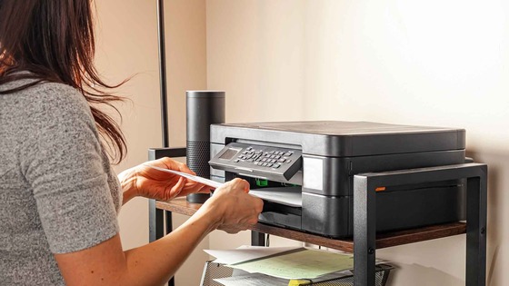 person pulling paper from printer tray