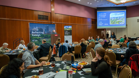 Reflecting Raleigh - An image of a speaker in front of an audience at a community conversation