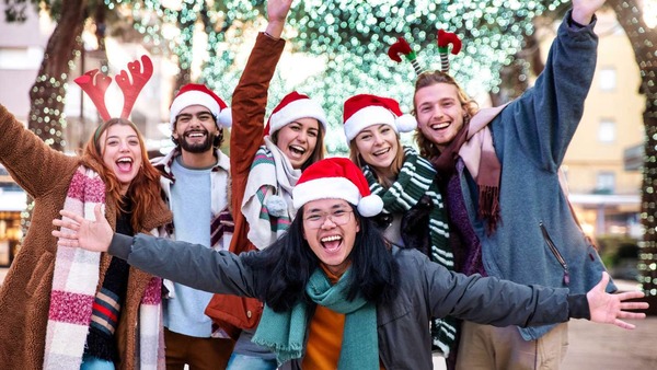 A group of people wearing Santa hats, scarves, and other holiday gear