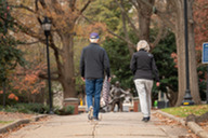 A couple walk through Nash Square Park, with fall trees around them.