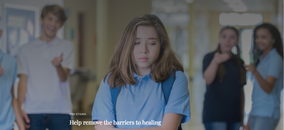 Teen looking depressed in school hallway with teens in background 