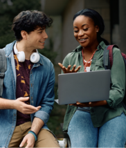 A high school student shows her laptop screen to a friend.