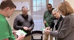 group of people standing talking while looking at information cards