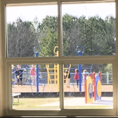 window looking out onto playground and adults and children on playground