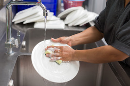 Washing dishes at food facility 