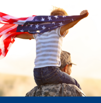 Veteran carrying a young child on his shoulders who is waving an American flag