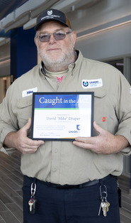 Mike Draper holding a certificate for the spring 2026 Caught in the Act Award