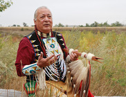 Native American Keith Bear wearing traditional regalia and talking with his hands