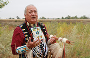 Native American Keith Bear wearing traditional regalia and talking with his hands