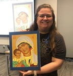 a female artist holding a framed painting she made