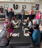 NDCA Board and staff standing, sitting and visiting during Belcourt Community Reception, June 2025