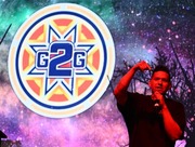 Native American rap artist Stuart James performing on stage, into a mic, with bright colors and the G2G logo behind him