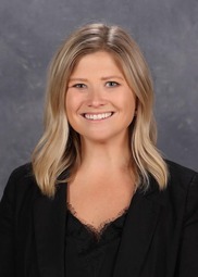 head and shoulders of caucasian Kierstin Hurtt with thick, wavy, shoulder-length blonde hair and a big toothy smile, wearing a black v-neck sweater