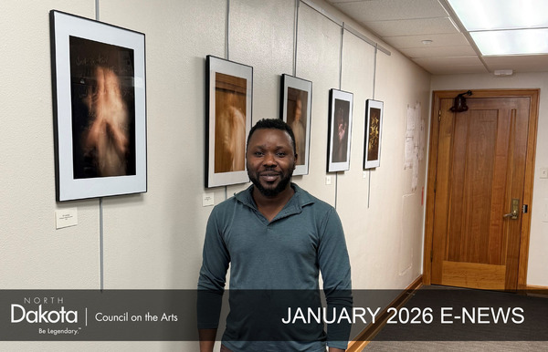 African American man, Ekow Ephrim, standing in a hallway that is featuring his photography on the walls