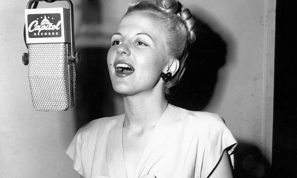 Black/white of Peggy Lee, a famous 1900's singer & actor, singing into a mic with her hair up, provided by Photo Credit: ND Music Hall of Fam