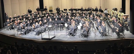 Mandan Middle School band playing on a large stage with black curtains all around