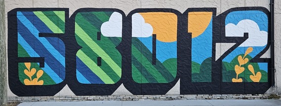 Huge outdoor mural showing the Castleton, ND zip code of 58012 in bold font with bright images of nature painted inside by Lauren Starling