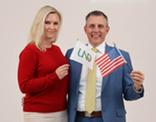 Professional photo of Governor and First Lady Armstrong holding an American and UND Flag