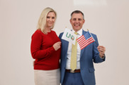 Professional photo of Governor and First Lady Armstrong holding an American and UND Flag
